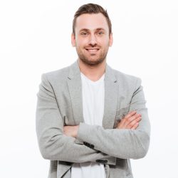 Portrait of successful man having stubble posing on camera with Portrait of successful man having stubble posing on camera with broad smile keeping arms folded isolated over white background